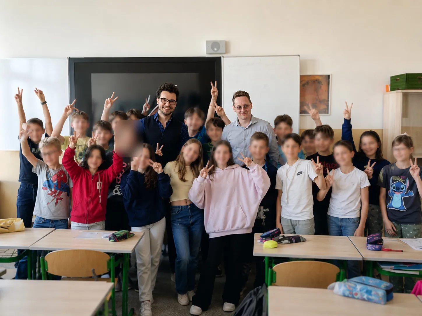 Matěj s kolegou stojí před třídou žáků po workshopu Safe4Future, děti mají zvednuté ruce.
